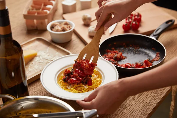 kadın tavada spagetti plaka üzerine koyarak domates kadeh kırpılmış