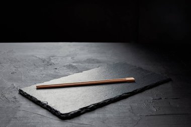 close-up view of slate board and chopsticks on black  clipart
