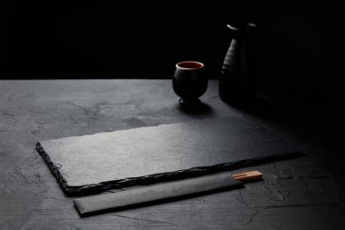 boş siyah arduvaz kurulu, yemek çubukları, sürahi ve kupa