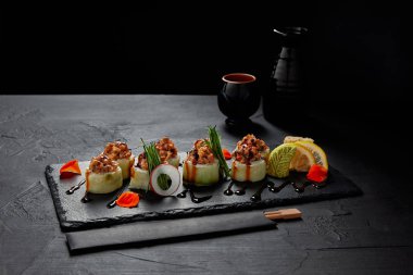 gourmet sushi roll with creamy eel and kimchi mayonnaise on slate board and chopsticks  