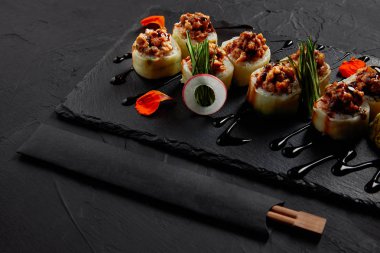 delicious sushi roll with creamy eel and kimchi mayonnaise on slate board and chopsticks   clipart