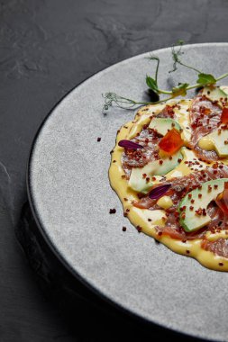 dilimlenmiş balık ve avokado sos ile Japon yemek gurme siyah plaka üzerinde görmek