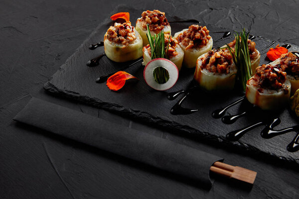 delicious sushi roll with creamy eel and kimchi mayonnaise on slate board and chopsticks  