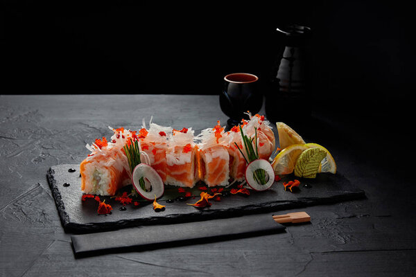 close-up view of delicious delicious roll in mamenori with shrimp, salmon and avocado on slate board
