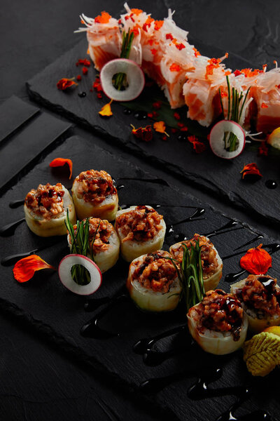 close-up view of roll in mamenori with shrimp, salmon and avocado in sauce nigiri and roll with creamy eel and kimchi mayonnaise 