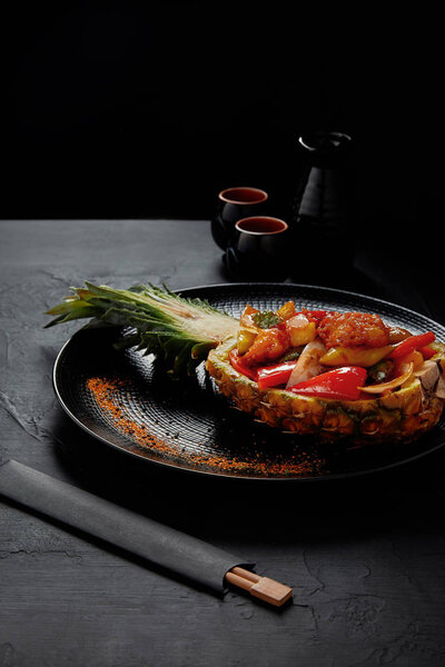 деликатесы японской кухни подаются в половину жареного ананаса и палочки для еды
