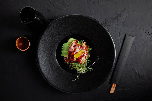 top view of Japanese Ceviche with seafood, avocado and herbs on black plate 