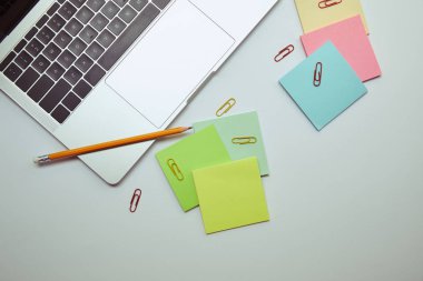 beyaz masa üzerinde laptop, Kağıt etiketleri, kalem ve kağıt klipleri üstten görünüm