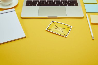 Kağıt etiketleri, mesaj işareti ve sarı yüzey üstünde laptop