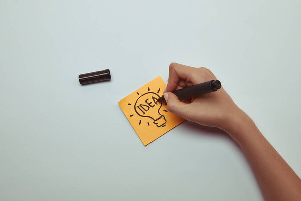 cropped image of woman drawing word idea in lightbulb on paper sticker