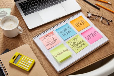 iş stratejisi, hesap makinesi, fincan kahve ve masa üstünde laptop ile kağıt sopa