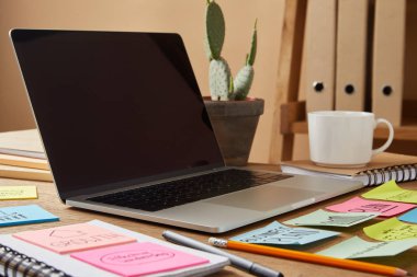Laptop ile boş bir ekran ve Kağıt etiketleri ve kaktüs masa üzerinde