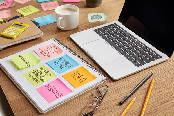 paper stickers with business strategy, glasses and laptop on tabletop