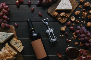 şarap şişesi boş etiket, tirbuşon ve çeşitli lezzetli atıştırmalıklar ile üstten görünüm ahşap tablo 