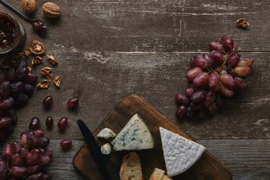 top view of fresh ripe grapes, walnuts, cheese and delicious jam on wooden table   clipart