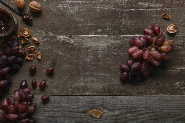 top view of fresh ripe grapes, walnuts and delicious jam on wooden table  clipart