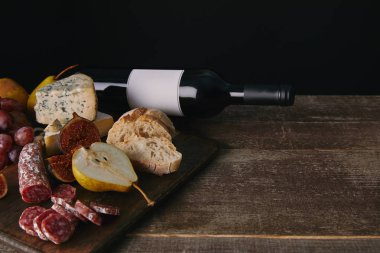 şişe şarap boş etiket, meyve ve lezzetli aperatifler ile ahşap masa üzerinde görmek