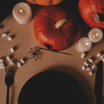 Top view of pumpkins, black plate, fork and knife with marshmallows on table, halloween concept