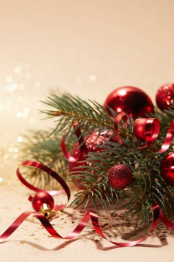 kırmızı parlak Noel topları, dalgalı şerit ve ışıltılı masa üstü çam dalı