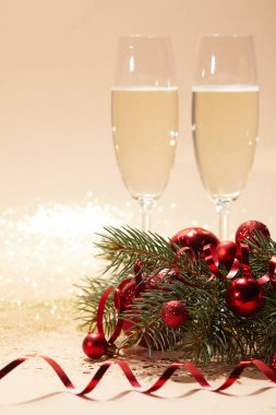 iki kadeh şampanya, neşeli Noel topları ve ışıltılı masa üstü çam dalı