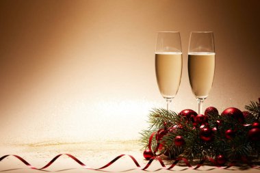 glasses of champagne, christmas balls and pine branch on glittering tabletop clipart