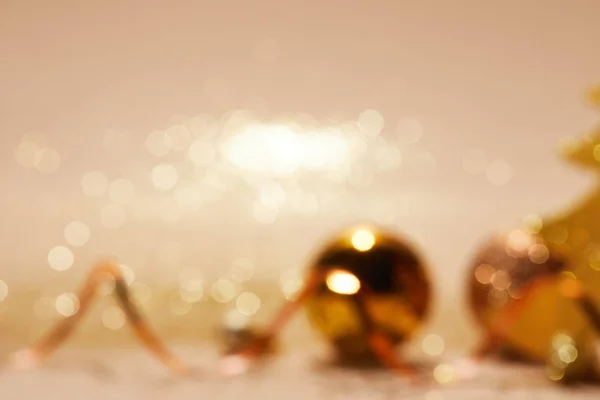 Unscharfe Weihnachtskugeln Und Welliges Band Auf Beiger Oberfläche — kostenloses Stockfoto