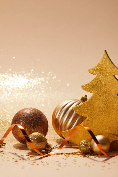 Рождественские шары, сверкающая елка и волнистая лента на столешнице
