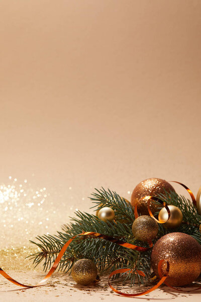 glittering golden christmas balls and christmas tree branch on tabletop