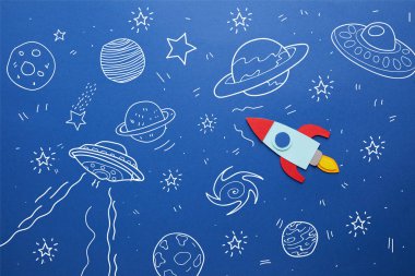 creative rocket on blue paper background with universe icons clipart