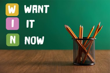 pencils on wooden table with green chalkboard on background with 