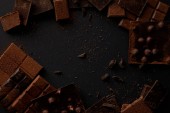 pohled shora na různé kousky lahodné čokolády na černém pozadí 