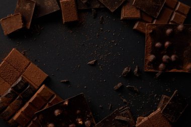 top view of various delicious chocolate pieces on black background  clipart