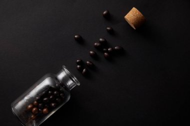 siyah gurme çikolata topları, cam kavanoz ve mantar üstten görünüm