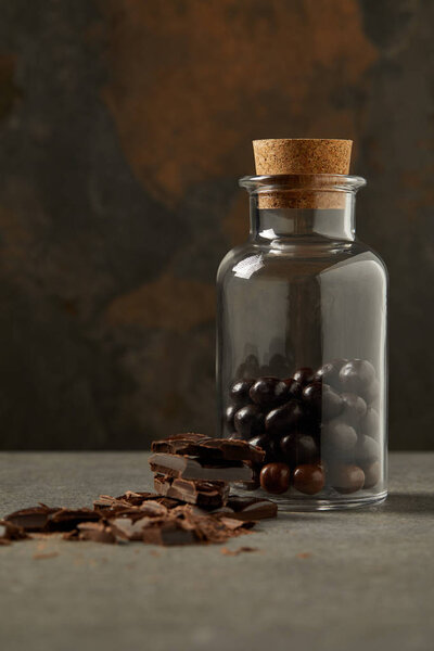 close-up view of chocolate pieces and gourmet chocolate balls in glass jar on grey