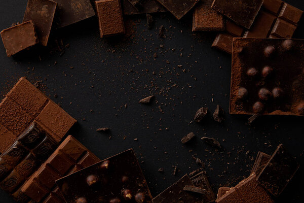 top view of various delicious chocolate pieces on black background 