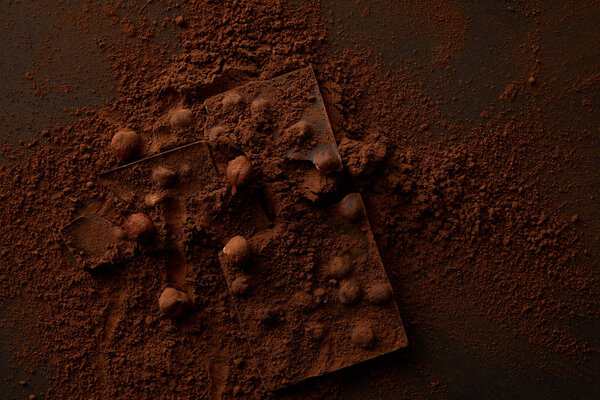 вид сверху на вкусные кусочки шоколада с орехами на темном фоне
