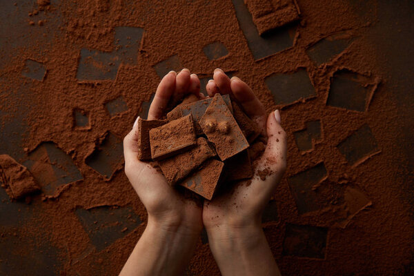 обрезанный кадр вкусных кусочков шоколада в человеческих руках
