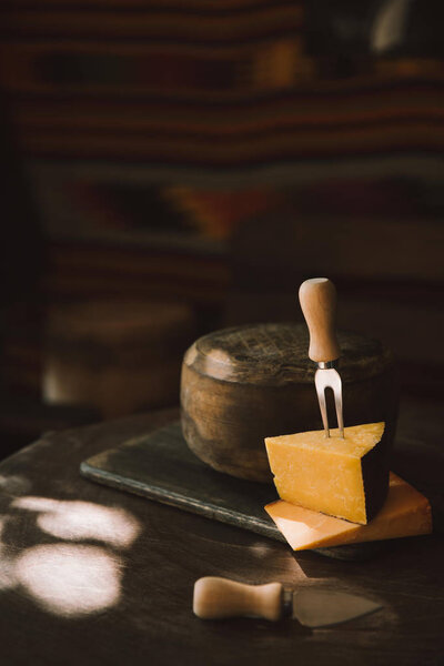 two sorts of cheese slices with fork on rustic wooden table