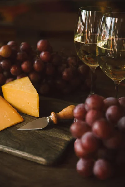 Nahaufnahme Von Scheibenkäse Mit Messer Trauben Und Weißwein Auf Schneidebrett — Stockfoto