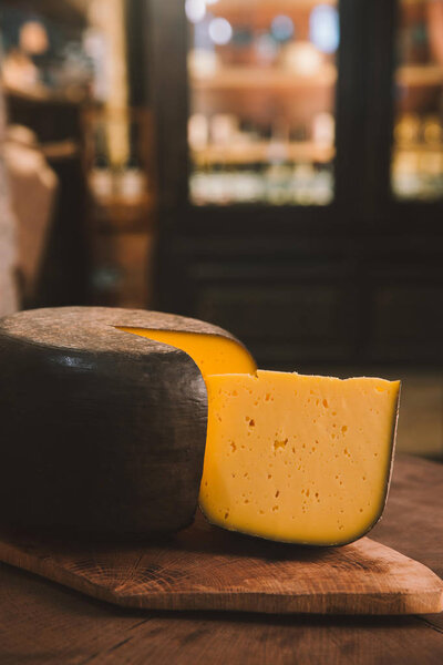 delicacy sliced cheese on rustic wooden cutting board in cheese store