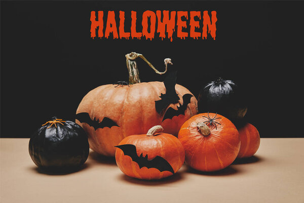 orange and black pumpkins with paper bats on table with "halloween" sign
