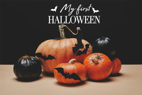 orange and black pumpkins with paper bats on table with bats and "my first halloween" lettering