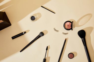 üstten görünüm çeşitli kozmetik ve bej masa üzerinde yalan yanlış eyelashes