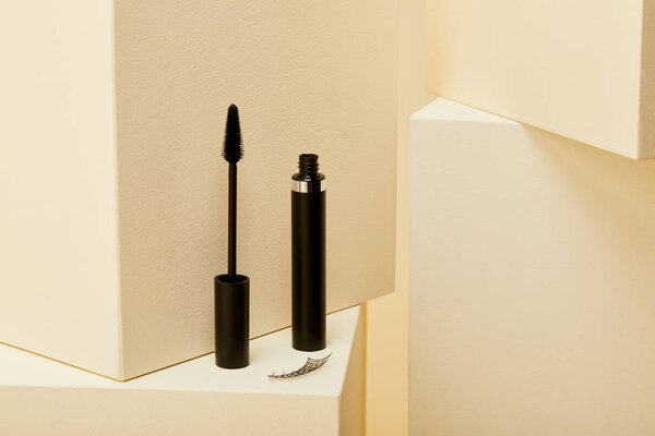 close-up shot of false eyelash and mascara on beige cube