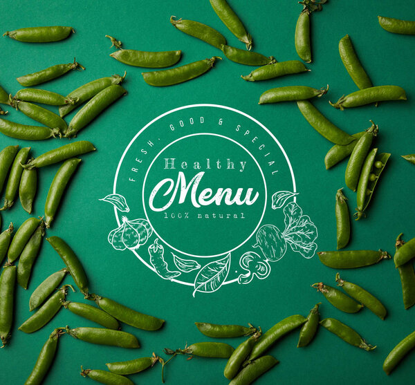 top view of round frame made of pea pods on green surface with "healthy menu" lettering