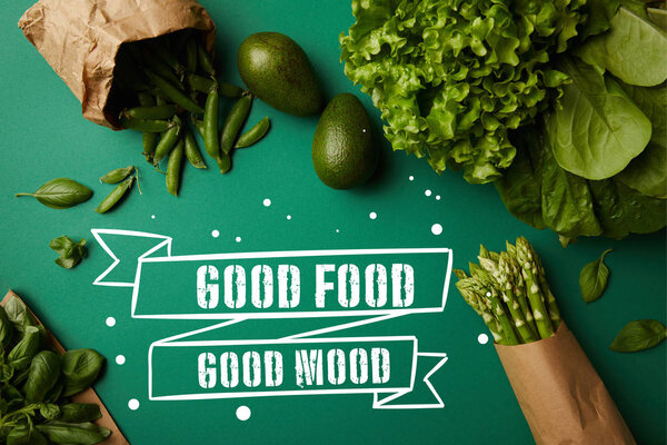 top view of different green ripe vegetables on green surface with "good food - good mood" inspiration