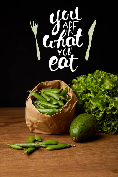 close-up shot of avocado, green peas and lettuce on wooden surface with "you are what you eat" inspiration