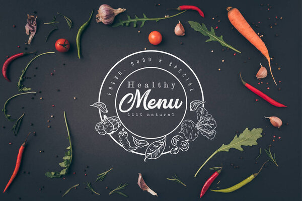 top view of arugula, carrot and chili peppers on gray surface with "healthy menu" lettering in seal