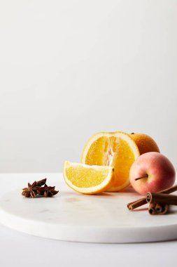 gri arka plan üzerinde beyaz yüzey üzerinde mulled şarap için taze elma, portakal ve baharat malzemelerin görünümü kadar kapatın 