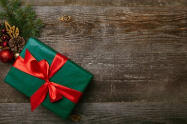 ahşap arka plan üzerinde kaydırılan yeşil kırmızı kurdele ve Noel oyuncaklar ile mevcut üstten görünüm